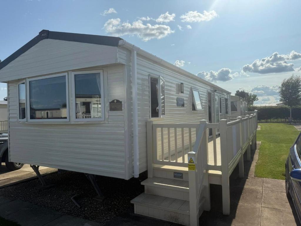Dieses weiße Mobilheim verfügt über eine Veranda und eine Treppe. in der Unterkunft Skegness Retreats The meadows 13 Golden Palm Resort Chapel st leonards in Chapel Saint Leonards