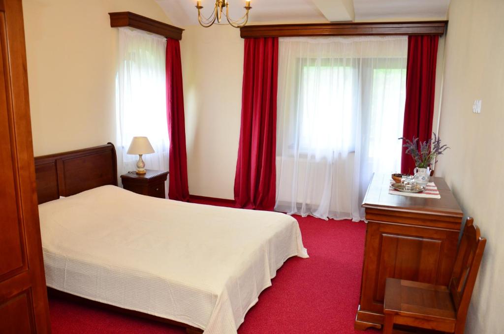 a bedroom with a white bed and red carpet at Pensiunea Valea Pinului in Rau Sadului