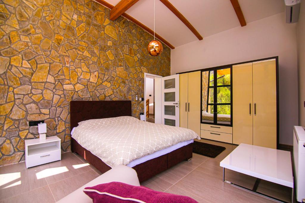 a bedroom with a bed and a stone wall at Golf Forest Creek Villas in Zavidovići