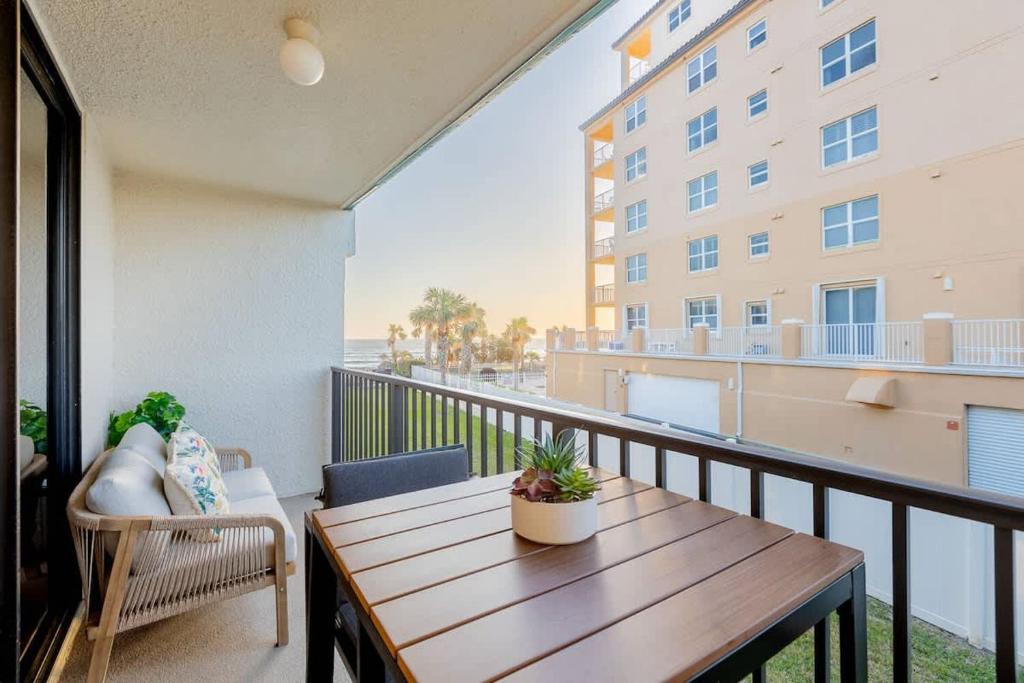 Un balcón con una mesa de madera y vista a un edificio. en Ocean Pool view I Beach front I Near Flagler 2BR, en New Smyrna Beach