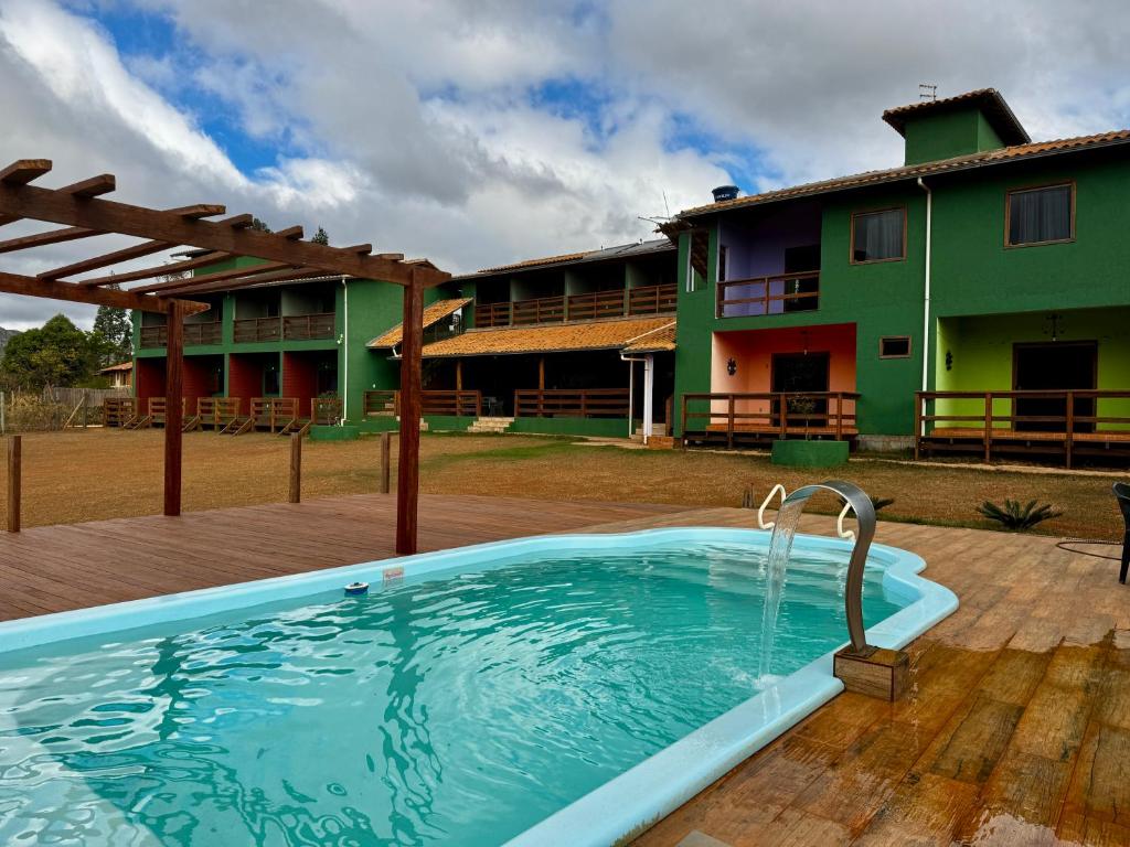 a pool in front of a building with a house at Pousada Bela Vista do Ismail - Lapinha da Serra in Santana do Riacho