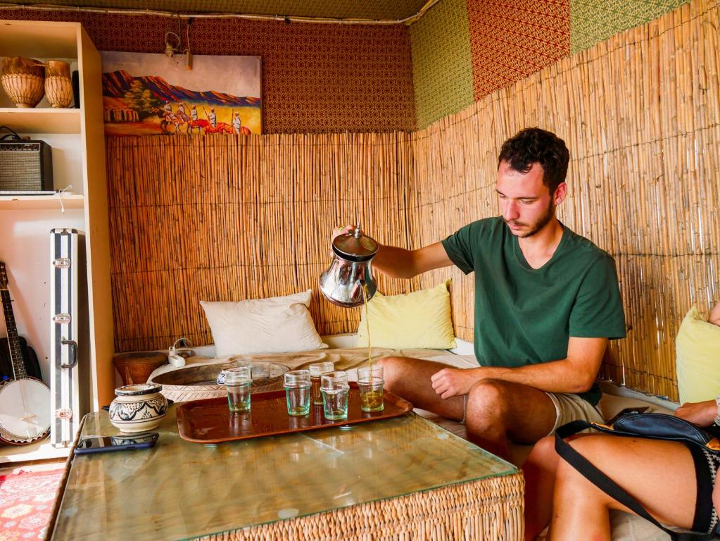 Un hombre sentado en una habitación con una tetera en caban surf Tamraght, en Tamraght Ouzdar