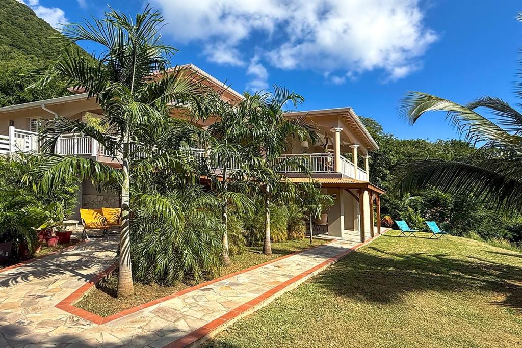 a house with palm trees in front of it at Perle d'Arlet in Les Anses-dʼArlets