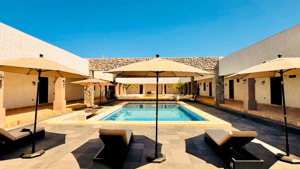 a swimming pool with umbrellas and chairs next to a building at Finca el Cielo San Carlos Sonora in San Carlos
