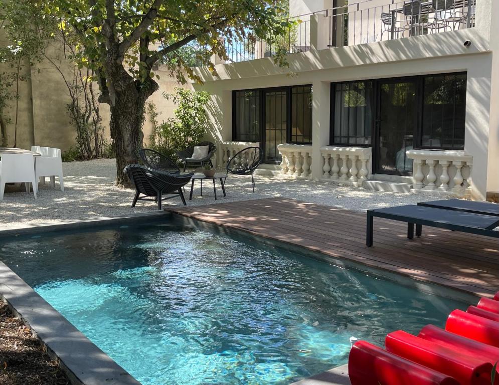 a swimming pool with red chairs and a table at Villa 47 SUD in Villeneuve-lès-Avignon