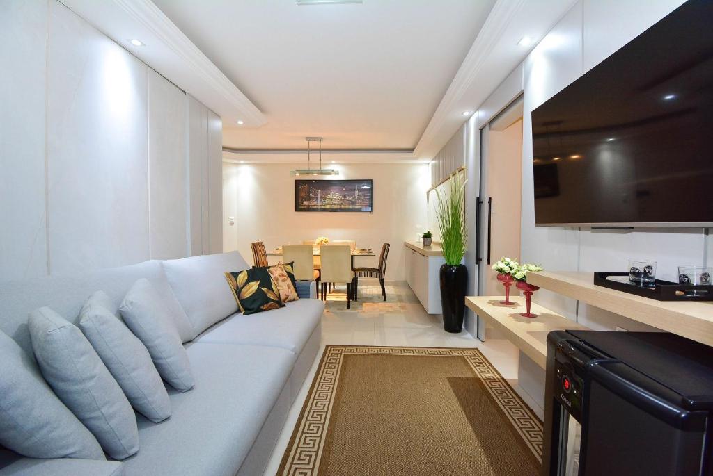sala de estar con sofá blanco y comedor en Aconchego em Itapema a 30 metros do Mar - ITA002, en Itapema