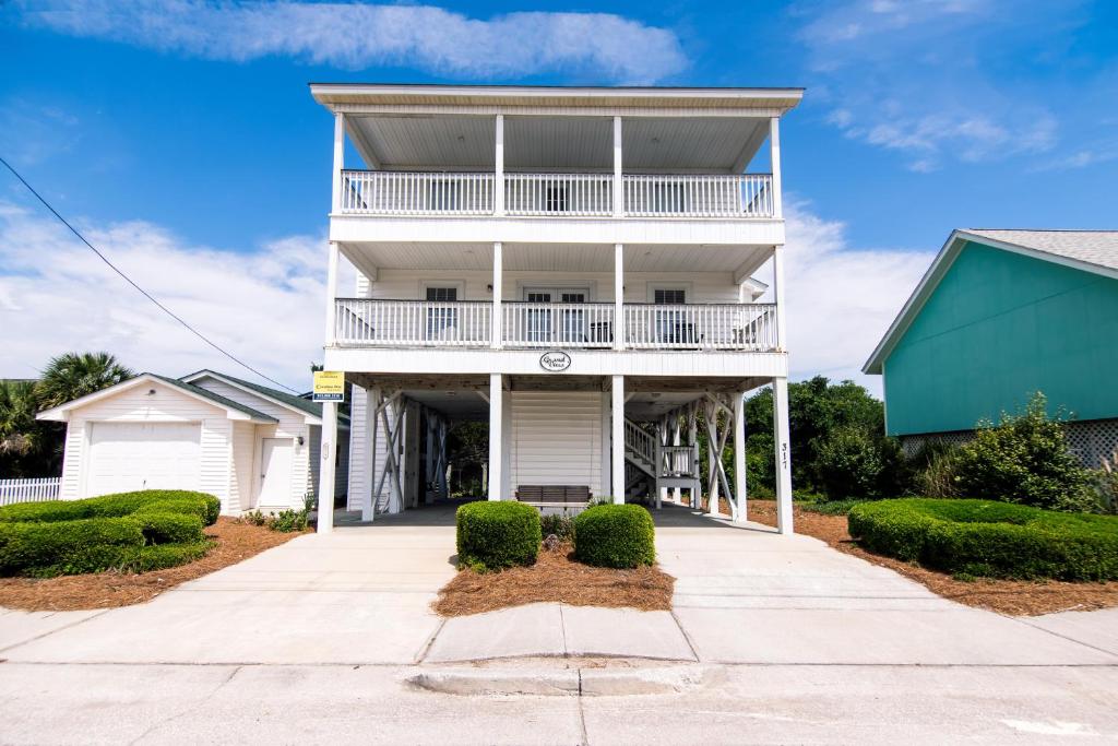 une maison blanche avec un balcon et des buissons dans l'établissement Grand View, à Edisto Island