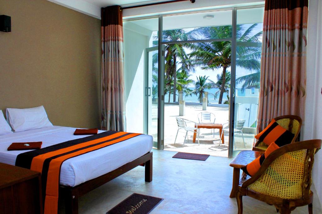 a bedroom with a bed and a balcony with a table and chairs at Saara Beach Hotel in Marawila