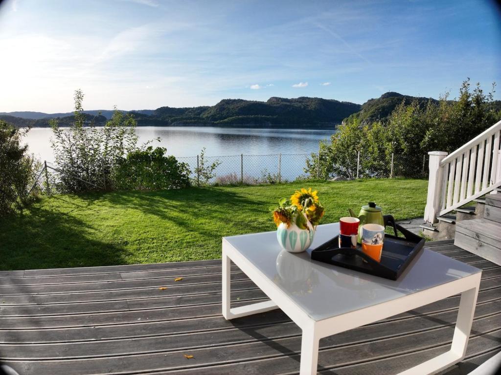 a white table on a deck with a view of a lake at Charming house by the sea in Svenevik