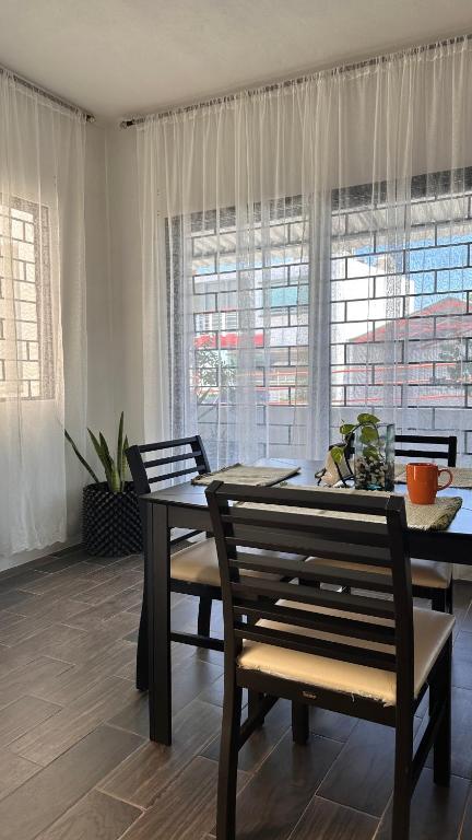 a dining room with a table and chairs and windows at Departamento moderno con wifi y AC in Ciudad del Carmen
