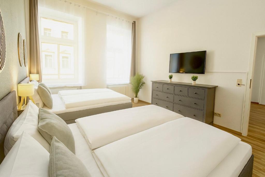a living room with white furniture and a flat screen tv at LUMA Apartments in Dresden
