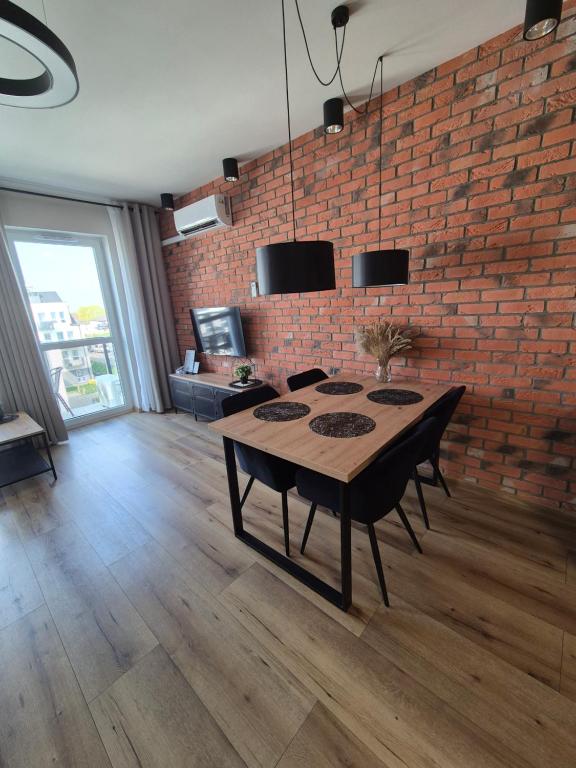een eetkamer met een tafel en een bakstenen muur bij Apartamenty blisko dworca in Stargard