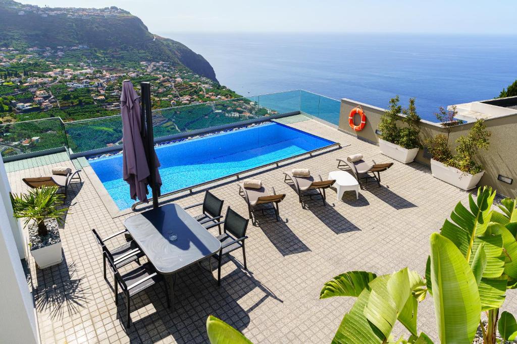 a view of a pool with chairs and an umbrella at Villa António in Arco da Calheta