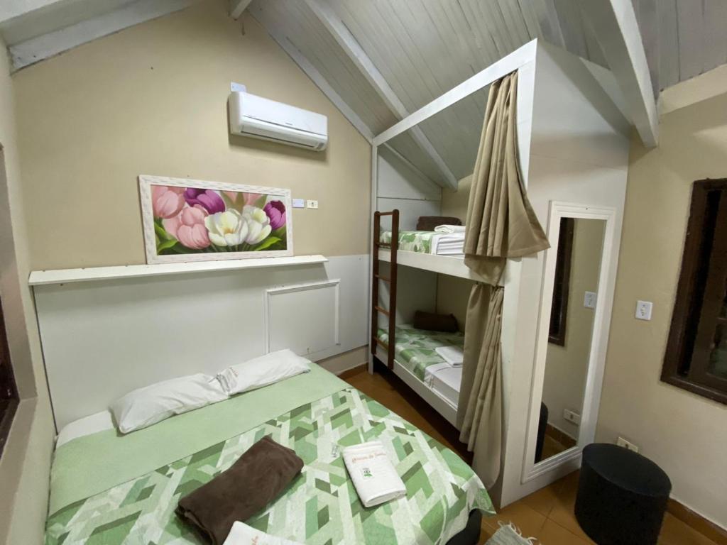 a small room with a bed and a bunk room with a mirror at Pousada Reserva do Tombo Lounge Hostel in Guarujá