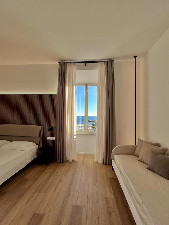 a bedroom with a bed and a couch and a window at Bianca Guesthouse in Civitavecchia