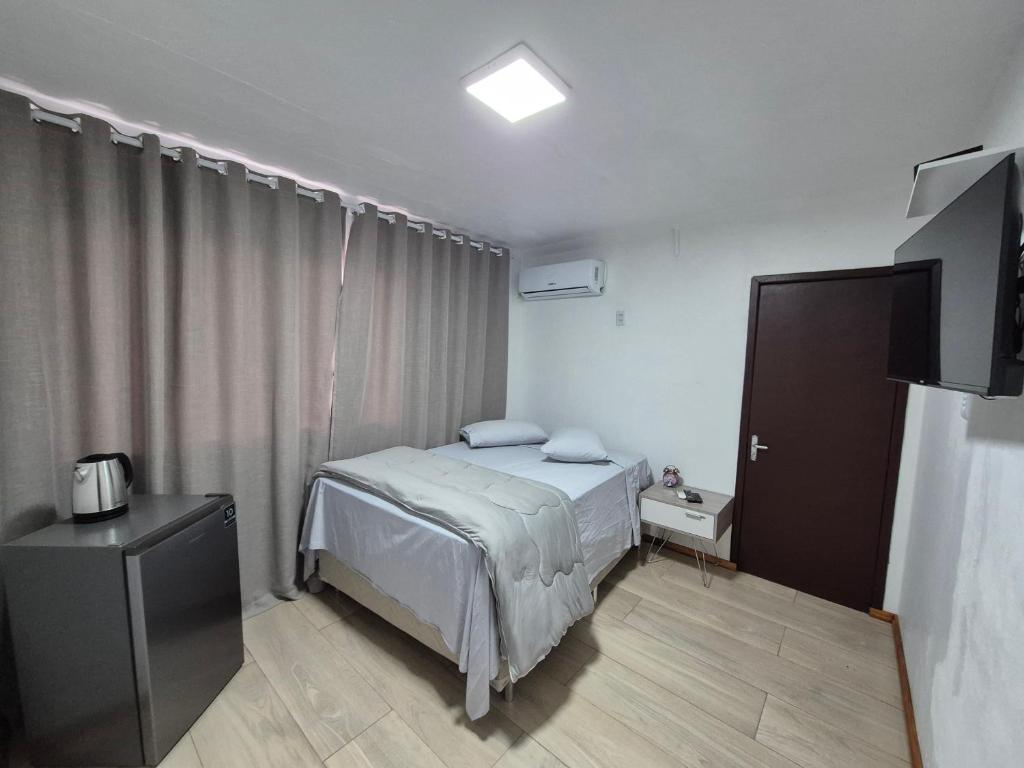 una piccola camera da letto con un letto e una televisione di Hotel El-Shaday a Vila Nova do Sul