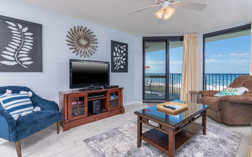 un soggiorno con una TV, un divano e un tavolo di Phoenix VI 6610 condo a Orange Beach