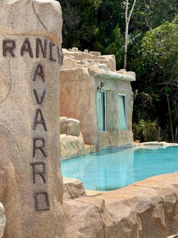 a swimming pool in a resort with a rock wall at Rancho Navarro - Caverna in Pôrto de Pedras