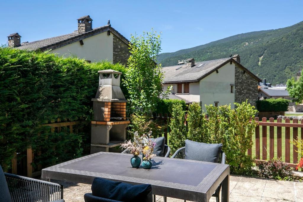 Un patio con mesa y sillas y una casa. en Paramita Adosado con Jardin, en Villanúa
