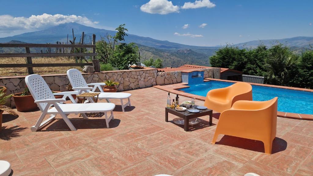 a patio with three chairs and a swimming pool at Casa Motta Camastra, panoramahouses, prive zwembad en prachtige vergezichten in Linguaglossa