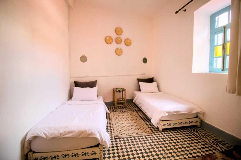 twee bedden in een kamer met een raam bij Dar janna in Essaouira