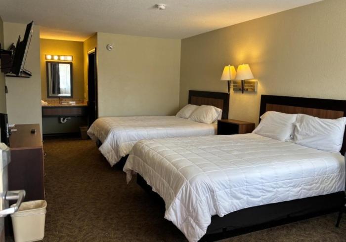a hotel room with two beds and a television at Twin Lakes Inn & RV Park in Stigler