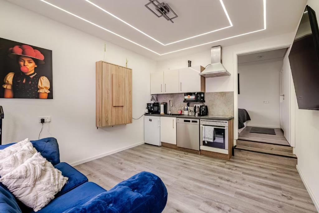 a living room with a blue couch and a kitchen at Ferienwohnung-Apartment Bollenhutzauber in Gutach