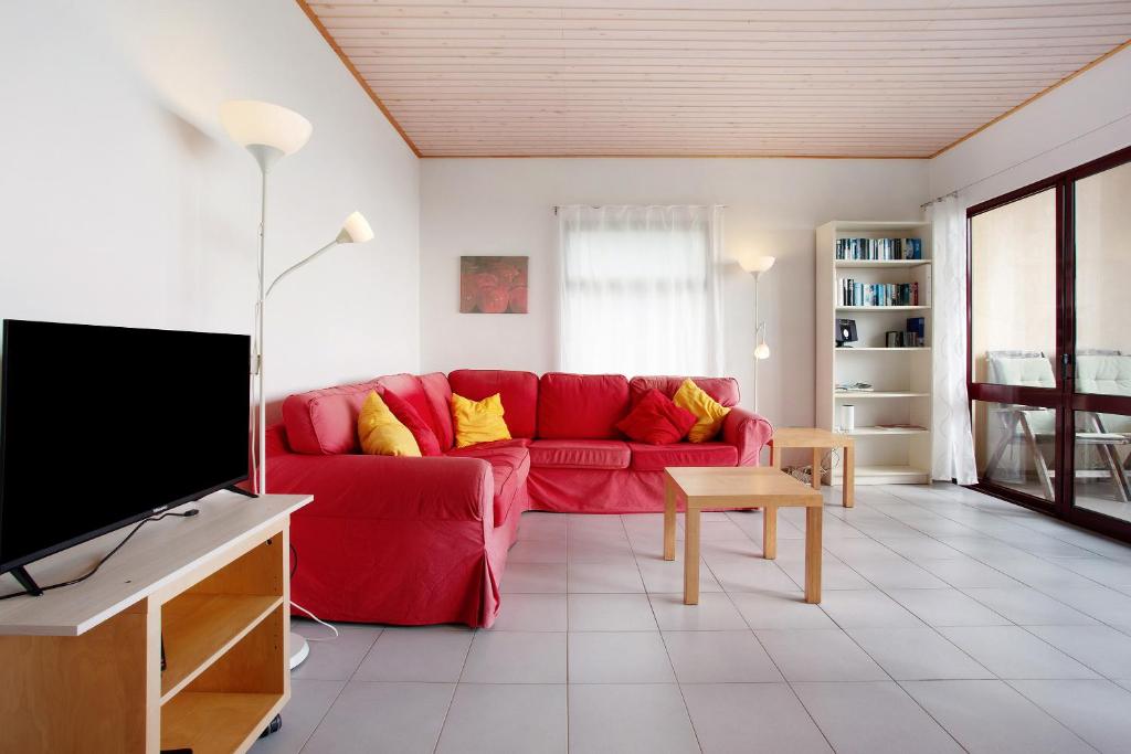 a living room with a red couch and a tv at Casa Conny in Caniço