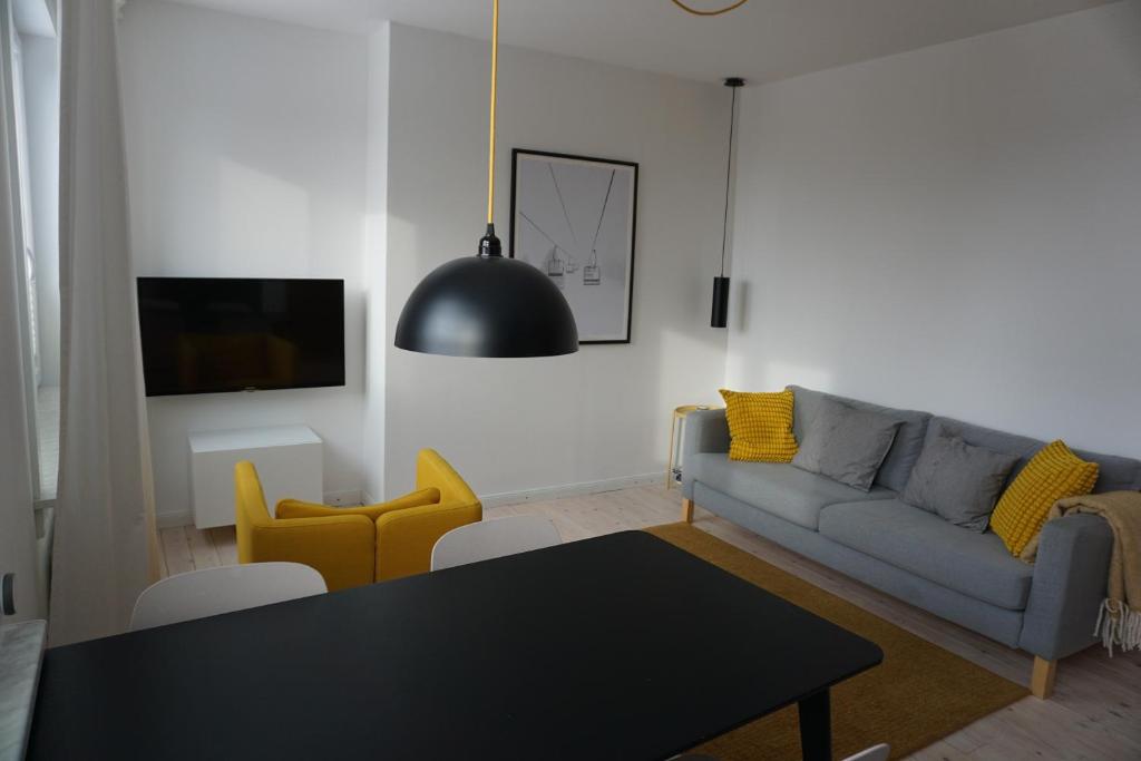 a living room with a couch and a table and yellow chairs at Muggelbude im Harz in Braunlage