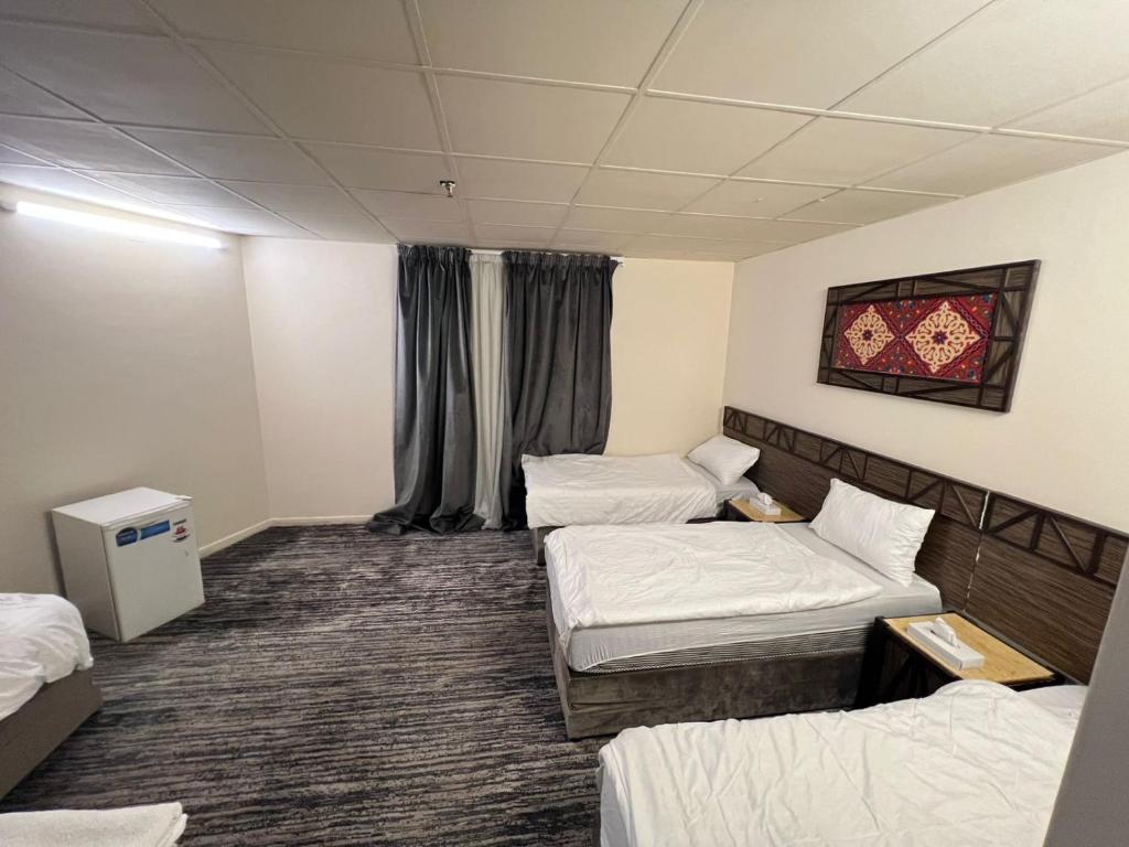 a hotel room with three beds in it at نزل الزائر 2 in Al Madinah