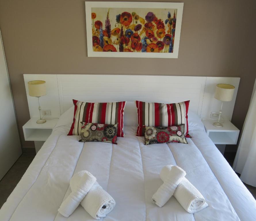 1 cama blanca con 2 toallas y 2 lámparas en Roca Aparts & Suites Tandil en Tandil