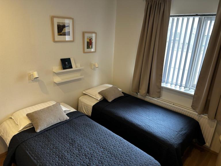 two twin beds in a room with a window at Flyers Hotel in Keflavík