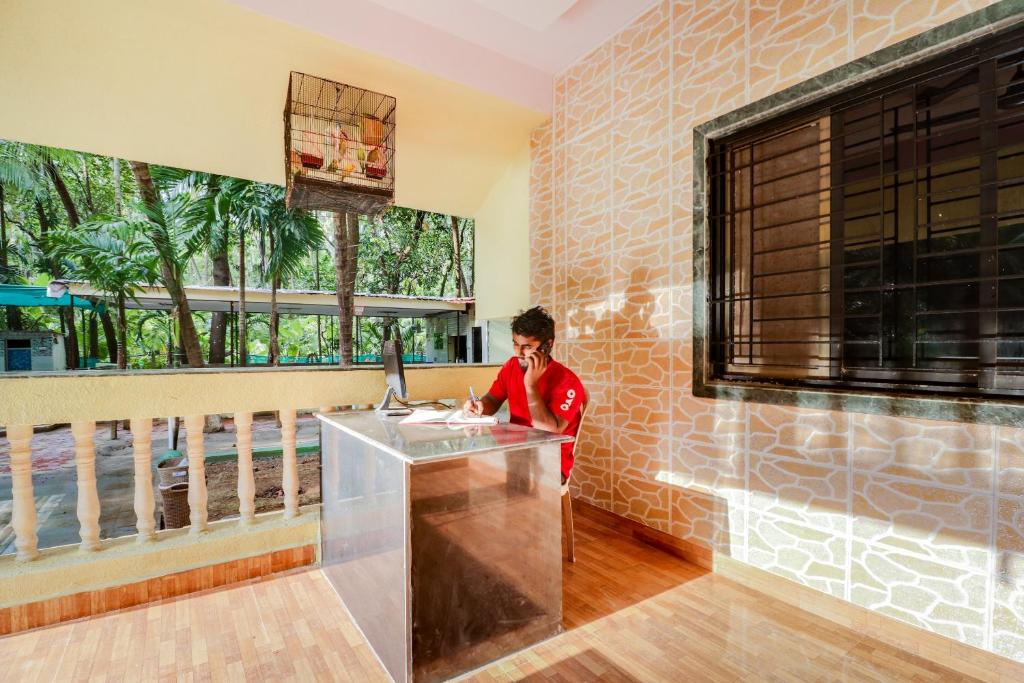 a person standing at a counter in a room with a window at Hotel O Nisarg Resort Satpati Beach in Satpati