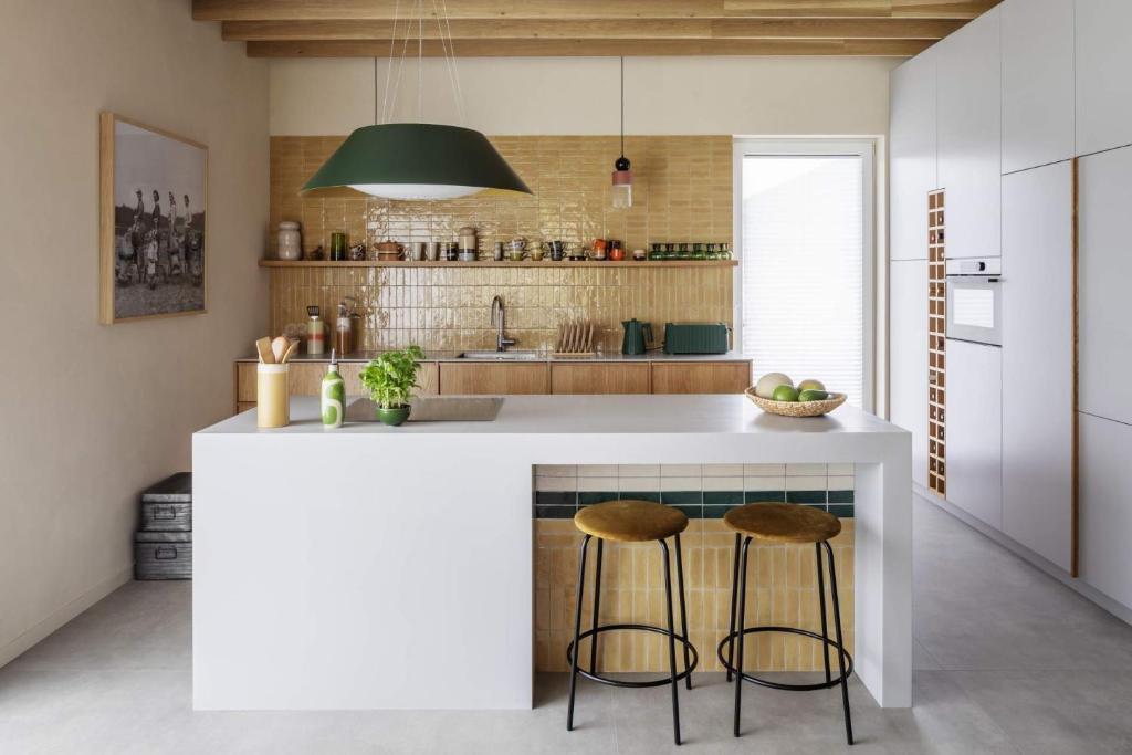 a kitchen with a white island with two bar stools at HYGGE Golf House in Gowinko