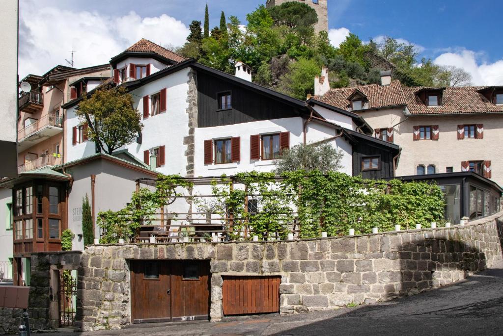 a white house with a stone wall at Boutique Hotel Santer Klause in Merano