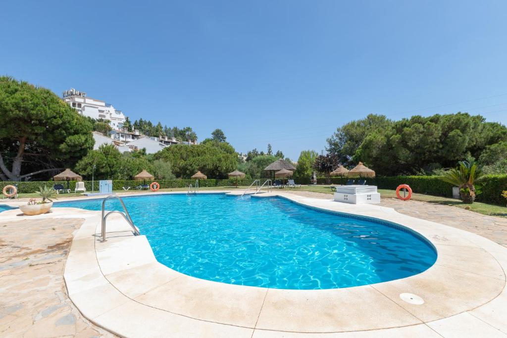 a swimming pool in a resort with trees and a building at Lovely 2 bed apt overlooking golf in Mijas Costa