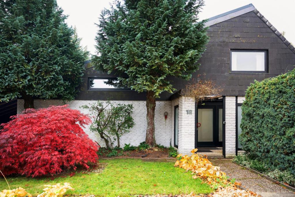 a house with a red bush in the front yard at Ferienwohnung Familie Franke in Joldelund