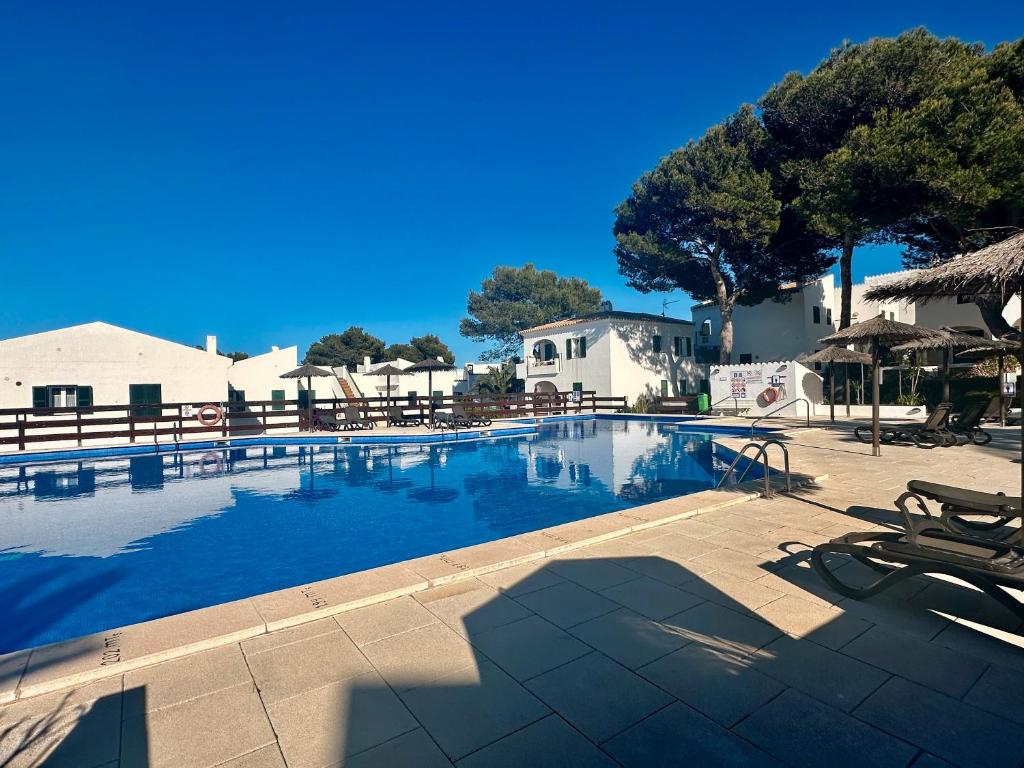 duży basen z krzesłami i parasolami w obiekcie Addaia w mieście Port d'Addaia