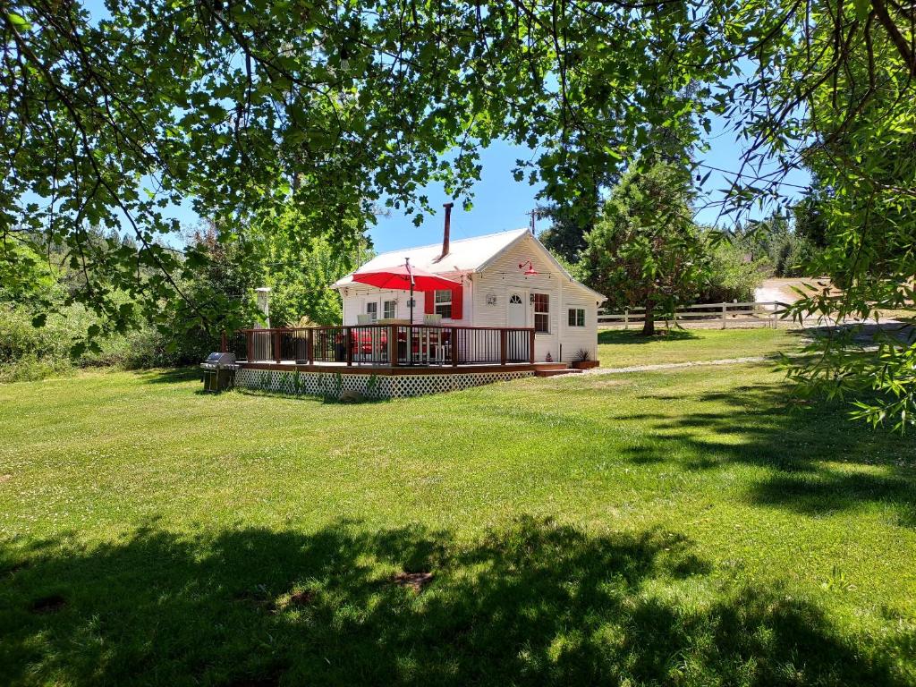 a house with a red roof on a grass field at Meadow Creek Cabin in Camino