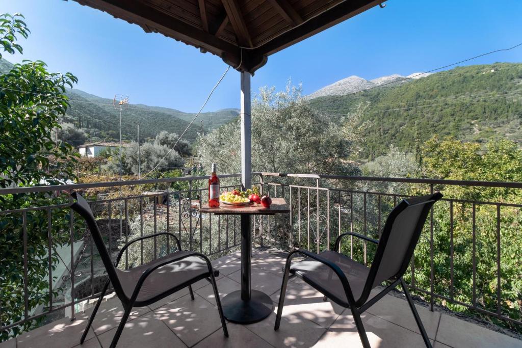 a balcony with a table and chairs and mountains at Krinos apartment 2 in Kharadhiátika