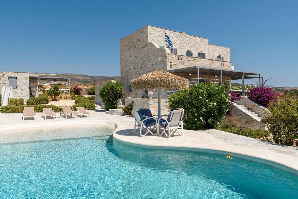 une piscine avec des chaises et un bâtiment dans l'établissement Aegean Seashell Villa, à Pounda