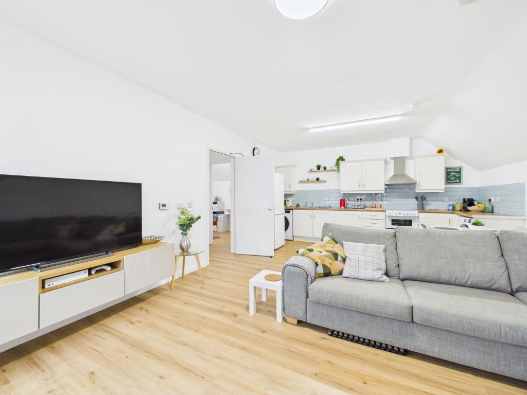 ein Wohnzimmer mit einem grauen Sofa und einem großen TV in der Unterkunft Kings Corner in Warrenpoint