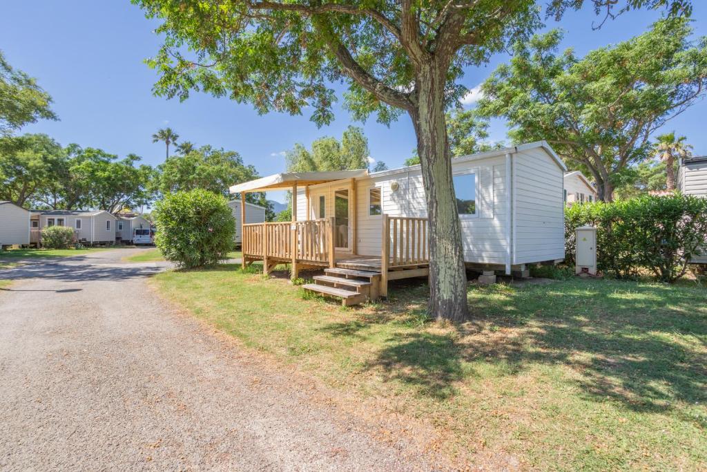 a tiny house with a porch next to a tree at Mobilhome 4 personnes in Argelès-sur-Mer