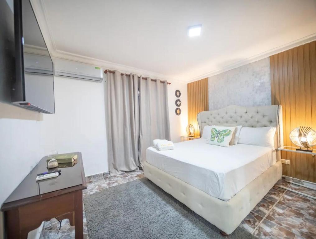 une chambre avec un lit blanc et une télévision dans l'établissement Stylish 1r-1b Apt Near The Beach And Main Street, à Sosúa