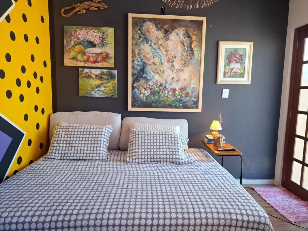 a bedroom with a bed and paintings on the wall at Casa chalé in Itajaí
