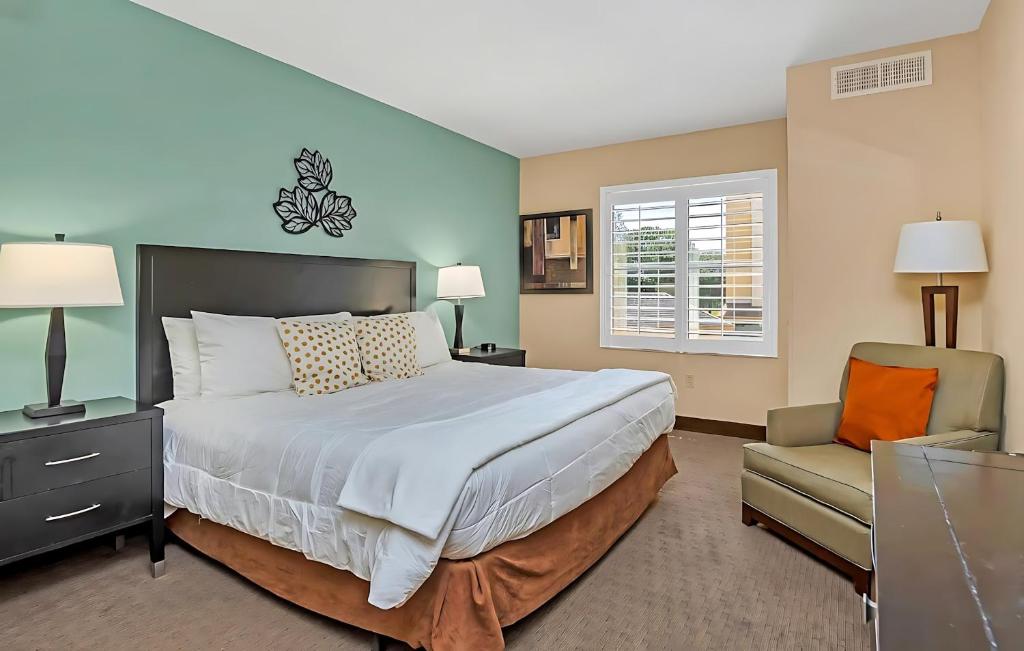 a bedroom with a large bed and a chair at Stylish King Apt w Arcade Game & BBQ Near Disney in Orlando