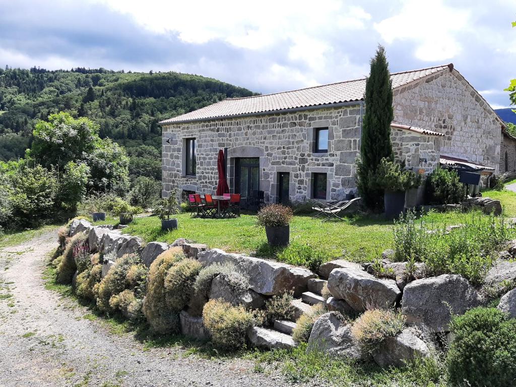 une maison en pierre sur une colline avec un mur en pierre dans l'établissement La clé des Champs, à Roche