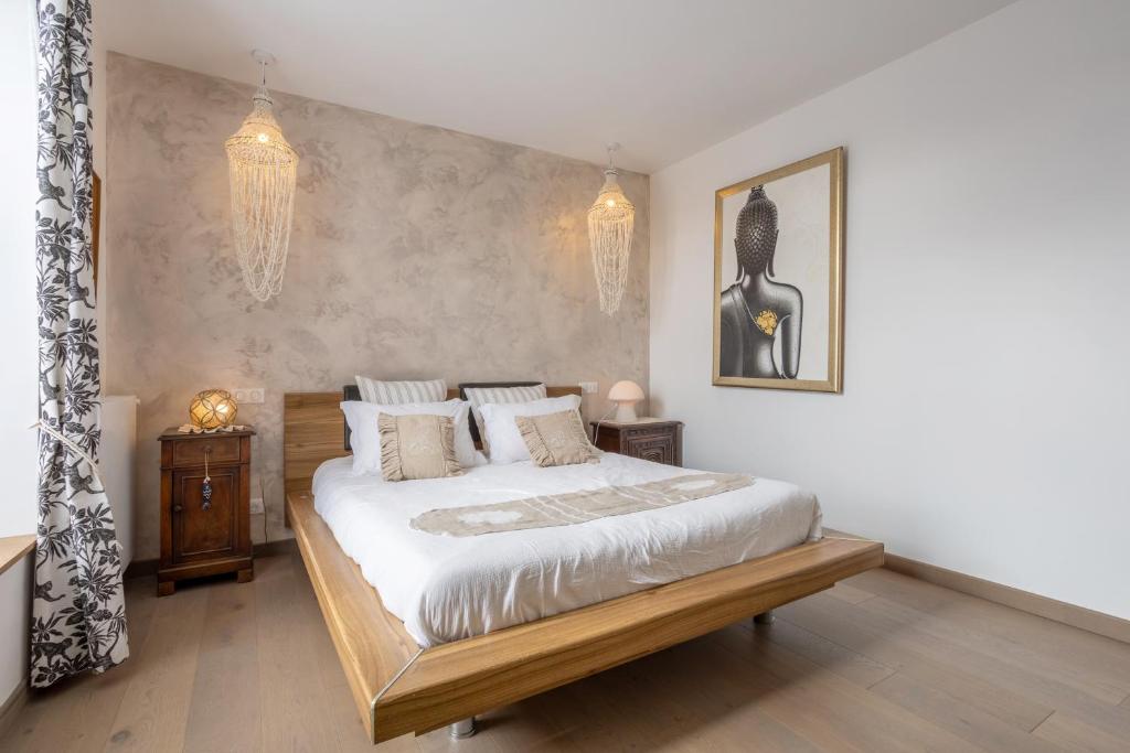 a bedroom with a large bed and a chandelier at Villa les Bleuets - proche Océan in Clohars-Carnoët