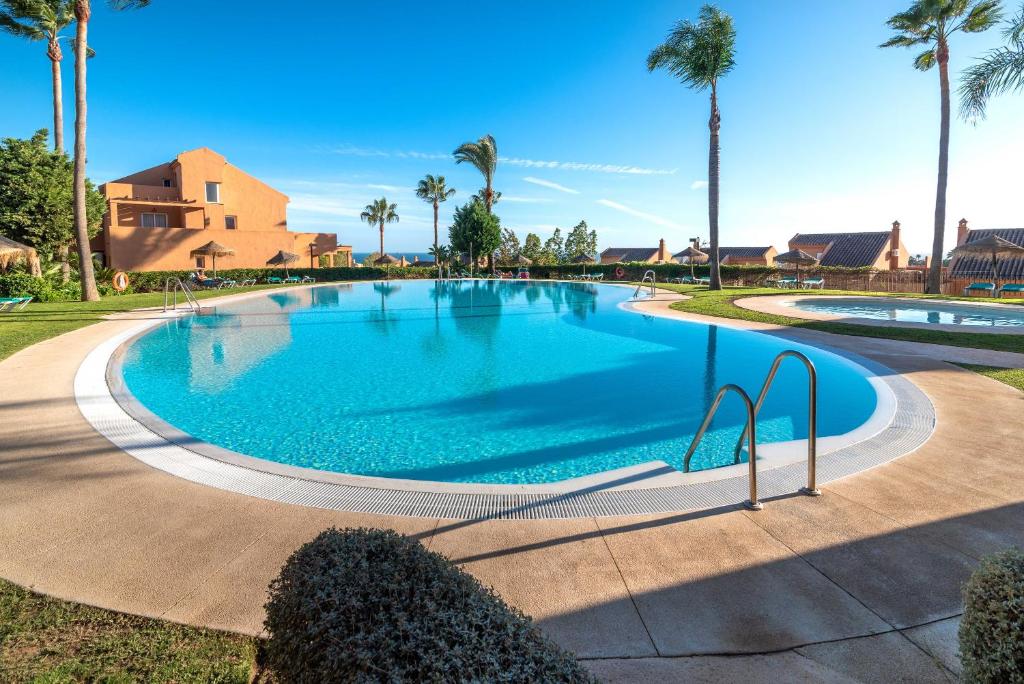 une grande piscine avec des palmiers en arrière-plan dans l'établissement Marbella Penthouse apartment, à Marbella