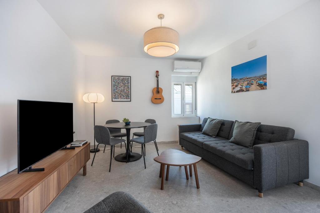 ein Wohnzimmer mit einer Couch, einem Fernseher und einem Tisch in der Unterkunft Ático San Jose in Cádiz